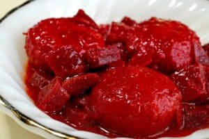 שתי ביצים קשות מכוסות ברוטב עגבניות וסלק אדום עשיר עם ירקות חתוכים לקוביות, מוגשות בצלחת לבנה.