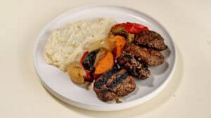 צלחת עם פירה, קציצות בשר בגריל וירקות צלויים.